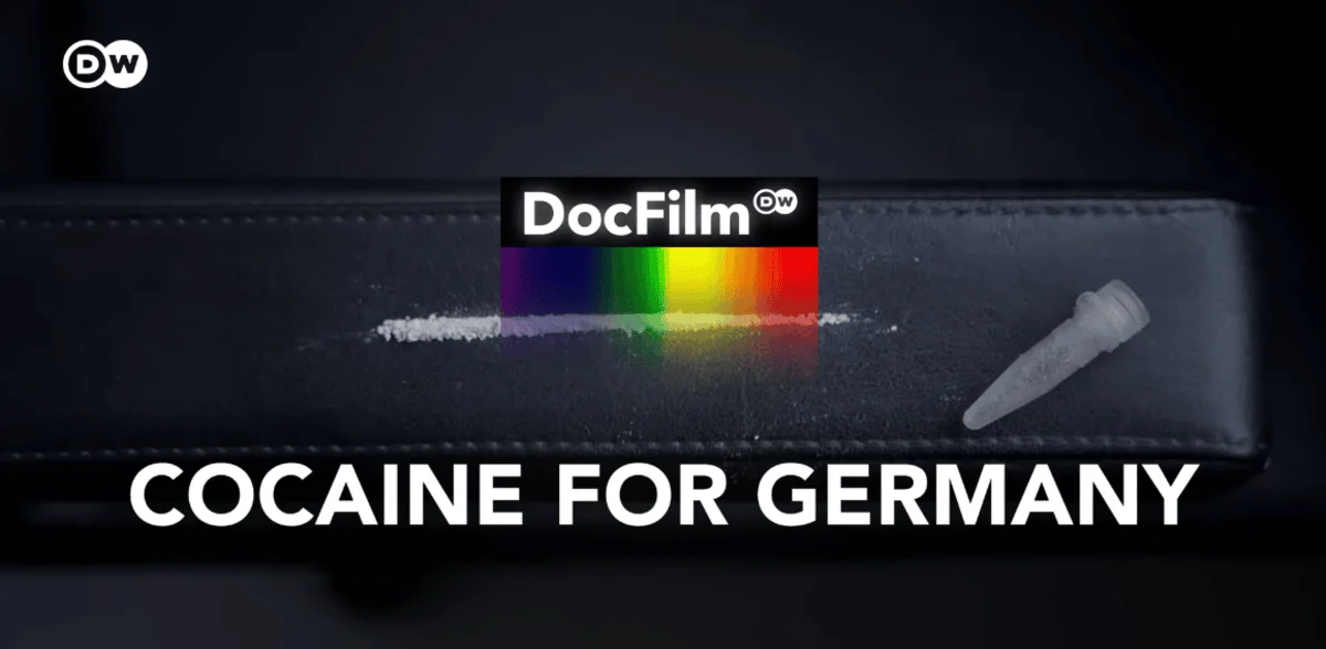 A line of white powder on a black surface next to a small plastic tube. 'DocFilm' logo with a rainbow stripe above the text 'Cocaine for Germany.'