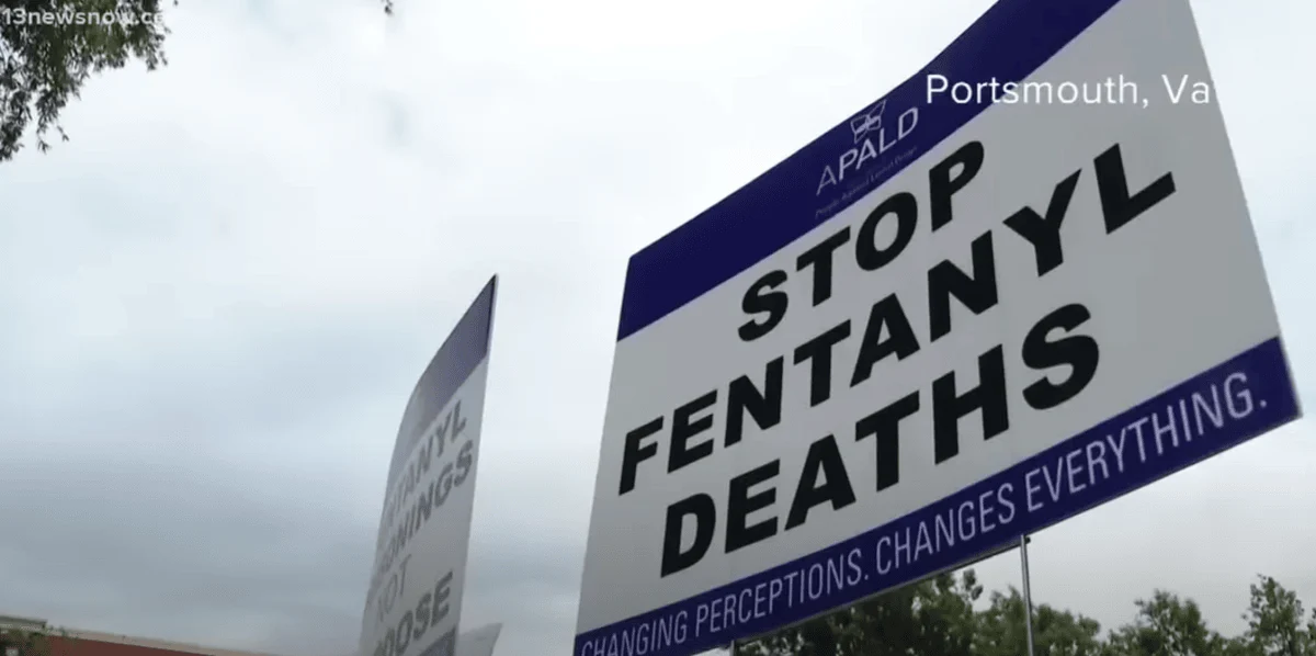 Cover for The Fentanyl Crisis featuring signs at a rally in Portsmouth, VA, read "Stop Fentanyl Deaths" and "Changing Perceptions, Changes Everything" against a cloudy sky backdrop.