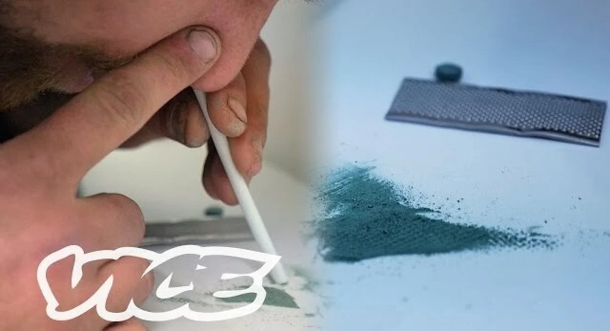 Close-up of someone's nose, with their finger covering one nostril and using a straw to sniff powdered fentanyl.