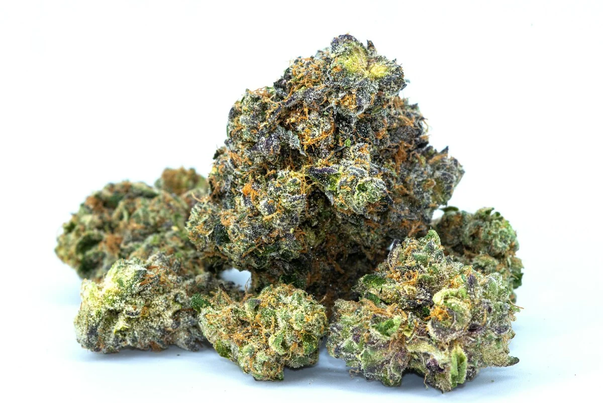 Dr. Andrew Huberman Close-up of frosted cannabis buds with purple hues and orange pistils against a white background.