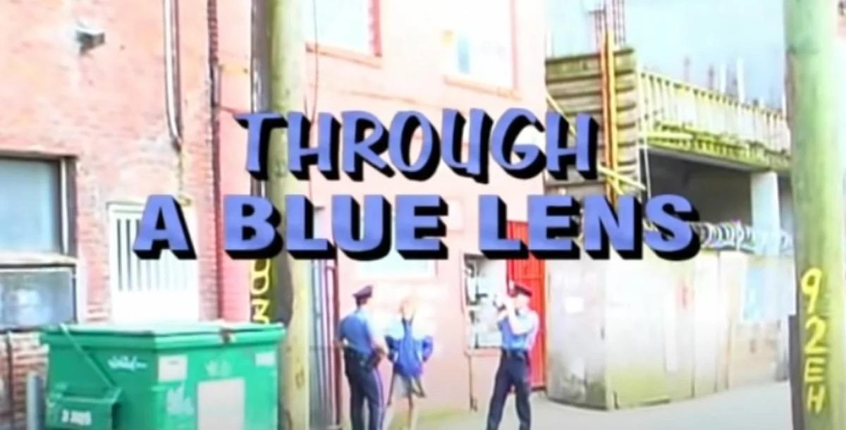 Text "Through a Blue Lens" is overlaid on a street scene with two police officers and a photographer in an urban alley, conveying an investigative tone.