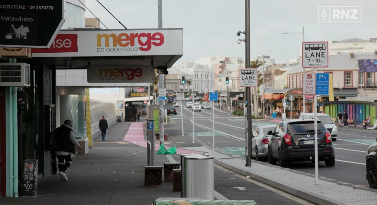 A street scene featuring parked cars alongside the Merge Community storefront.